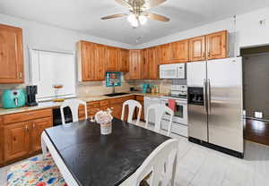 Kitchen with white appliances and stainless stell fridge, a ceiling fan, and brown cabinets