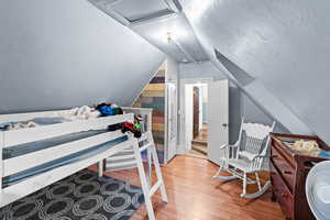 Bedroom featuring attic access, lofted ceiling, and light wood-type flooring