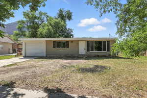 Ranch-style home featuring concrete driveway, a garage, a mountain view, and a front lawn