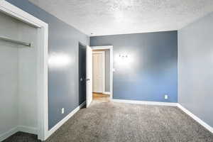 Bedroom with a textured ceiling, carpet, and a closet