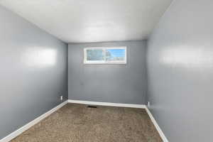 Bedroom with dark colored carpet and a textured ceiling