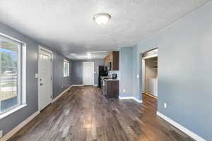 Living room with looking into the kitchen a textured ceiling and dark wood finished floors