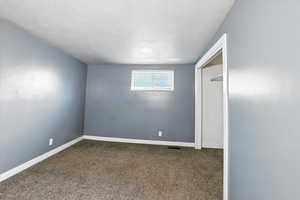 Bedroom with a textured ceiling, carpet, and a closet