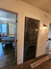 Laundry room featuring stacked washer / drying machine and dark wood-style floors