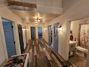 Hallway featuring stacked washing machine and dryer and dark wood-type flooring