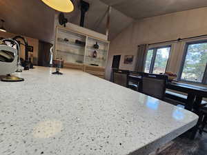 Kitchen with lofted ceiling, light stone counters, and open shelves