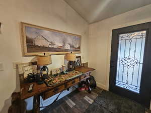 Foyer with wood finished floors and lofted ceiling