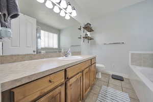 Bathroom featuring a bath, tile patterned floors, and vanity