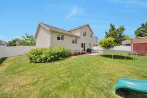 Rear view of house featuring a trampoline, a fenced backyard, and a shed