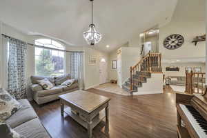 Living area with a chandelier, wood finished floors, stairway, high vaulted ceiling, and recessed lighting
