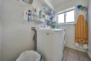 Laundry area featuring separate washer and dryer and light tile patterned floors
