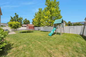 Fenced backyard with a playground and a storage unit