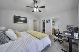 Bedroom with light colored carpet, vaulted ceiling, an office area, a walk in closet, and connected bathroom
