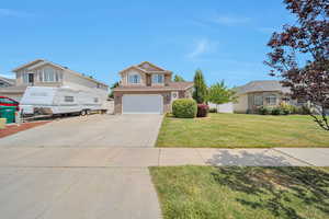 Traditional home with concrete driveway, an attached garage, a front yard, and brick siding