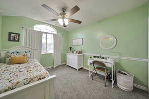 Carpeted bedroom with vaulted ceiling and ceiling fan