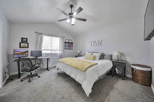 Carpeted bedroom with lofted ceiling, a desk, and a ceiling fan
