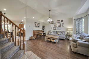 Living room featuring stairs, healthy amount of natural light, a chandelier, lofted ceiling, and recessed lighting