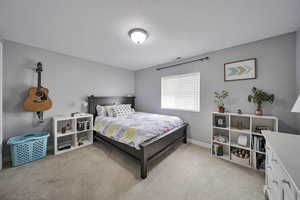 Bedroom featuring light carpet and baseboards