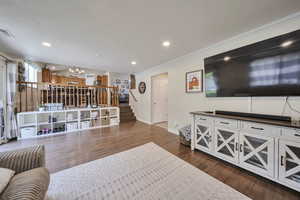 Living area with a chandelier, stairway, ornamental molding, dark wood-style floors, and recessed lighting