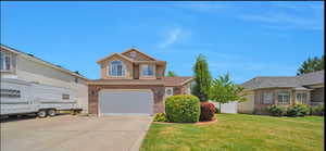 Traditional-style home with concrete driveway, a garage, a front yard, and brick siding