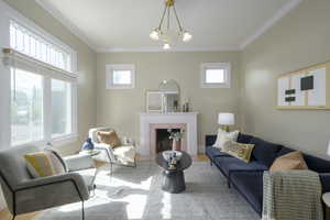 Living area featuring crown molding, a fireplace, a chandelier, and wood finished floors