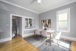 Dining room featuring ornamental molding, light wood-type flooring, and ceiling fan