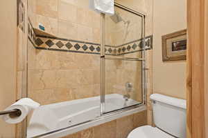 Bathroom with a combined bath / shower with jetted tub and toilet