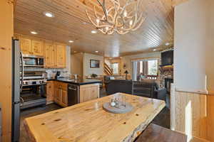 Dining area with recessed lighting, wood ceiling, stairs, a chandelier, and a stone fireplace