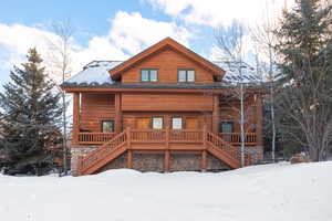 View of front of property featuring covered porch, stairway, and stone siding