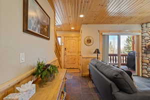 Living area featuring wood ceiling, a wainscoted wall, recessed lighting, stairway, and dark stone finish flooring