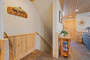 Stairs featuring stone tile floors, a wainscoted wall, recessed lighting, wooden walls, and wooden ceiling