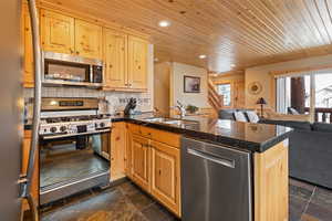 Kitchen featuring tile counters, appliances with stainless steel finishes, open floor plan, stone tile floors, and recessed lighting