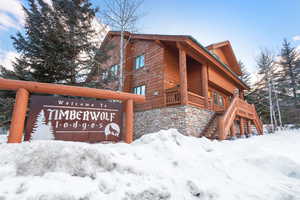 Snow covered property with stone siding