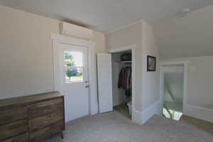 Unfurnished bedroom with carpet floors, a wall mounted AC, a closet, and lofted ceiling