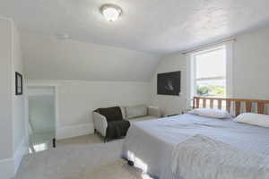Bedroom featuring a textured ceiling, lofted ceiling, and carpet flooring