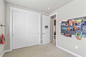Carpeted bedroom with baseboards and a closet