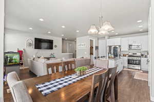 Dining space featuring a chandelier, dark wood-type flooring, and recessed lighting