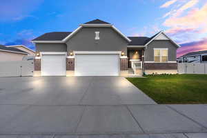Ranch-style house with a gate, brick siding, stucco siding, driveway, and an attached garage