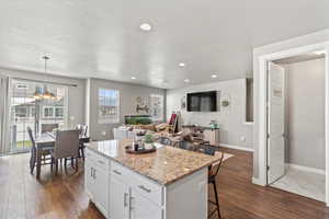Kitchen with a breakfast bar, white cabinets, a center island, and recessed lighting