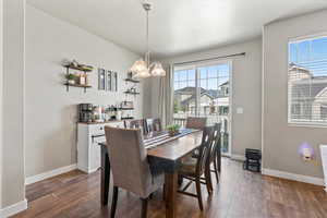 Dining area with dark wood-style floors and a chandelier
