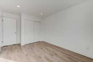 Unfurnished bedroom featuring light wood-style floors, a closet, and recessed lighting