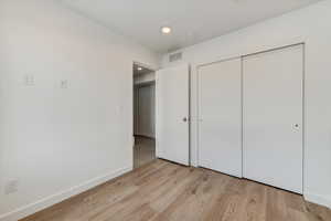Unfurnished bedroom featuring light wood-style flooring, a closet, and recessed lighting