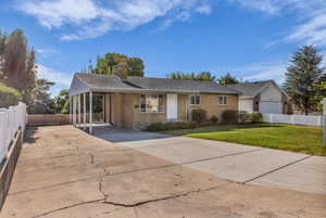 Ranch-style house featuring driveway, brick siding, a chimney, and a carport