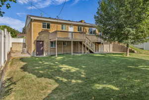 Back of property featuring brick siding, stairway, a deck, and a fenced backyard