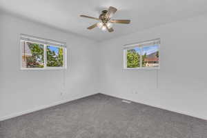 Carpeted spare room featuring baseboards and a ceiling fan