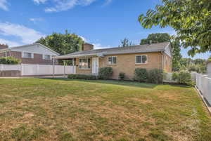 View of front of property featuring brick siding, a chimney, a fenced backyard, and a shingled roof