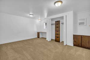Unfurnished bedroom with carpet and an office area