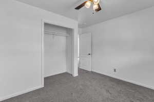 Unfurnished bedroom featuring carpet, a closet, and a ceiling fan