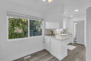 Kitchen featuring light countertops, plenty of natural light, white cabinets, light wood finished floors, and recessed lighting