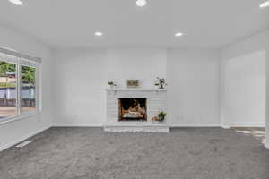 Unfurnished living room with carpet floors, recessed lighting, and a fireplace